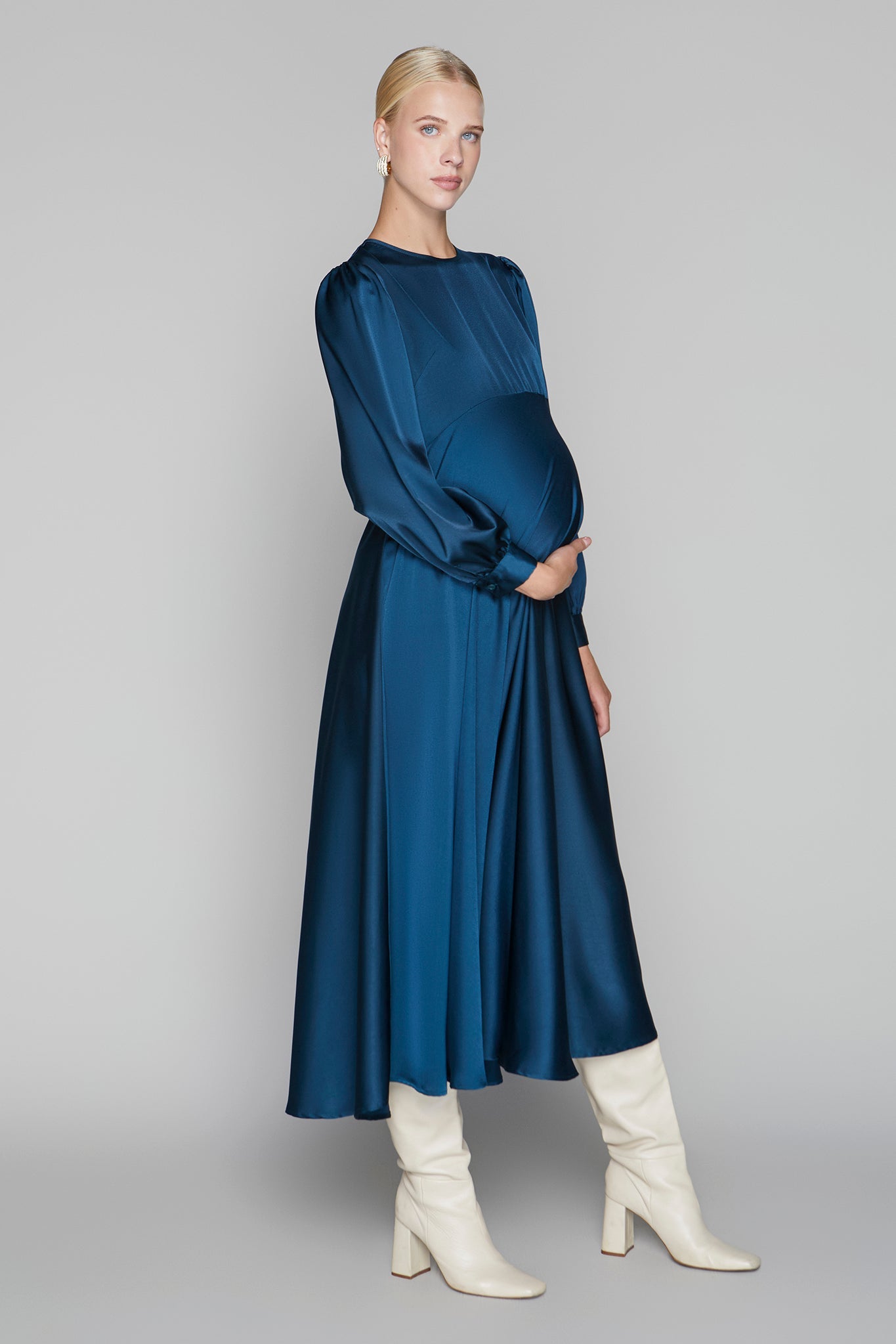 Woman wearing a blue dress and white boots on a gray background
