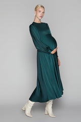 Woman wearing a dark green dress with long sleeves on a gray background