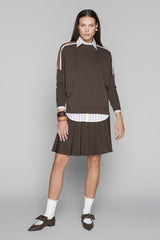Woman wearing a brown dress with white accents on a gray background