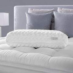 White contour pillow on a bed with gray headboard and pillows
