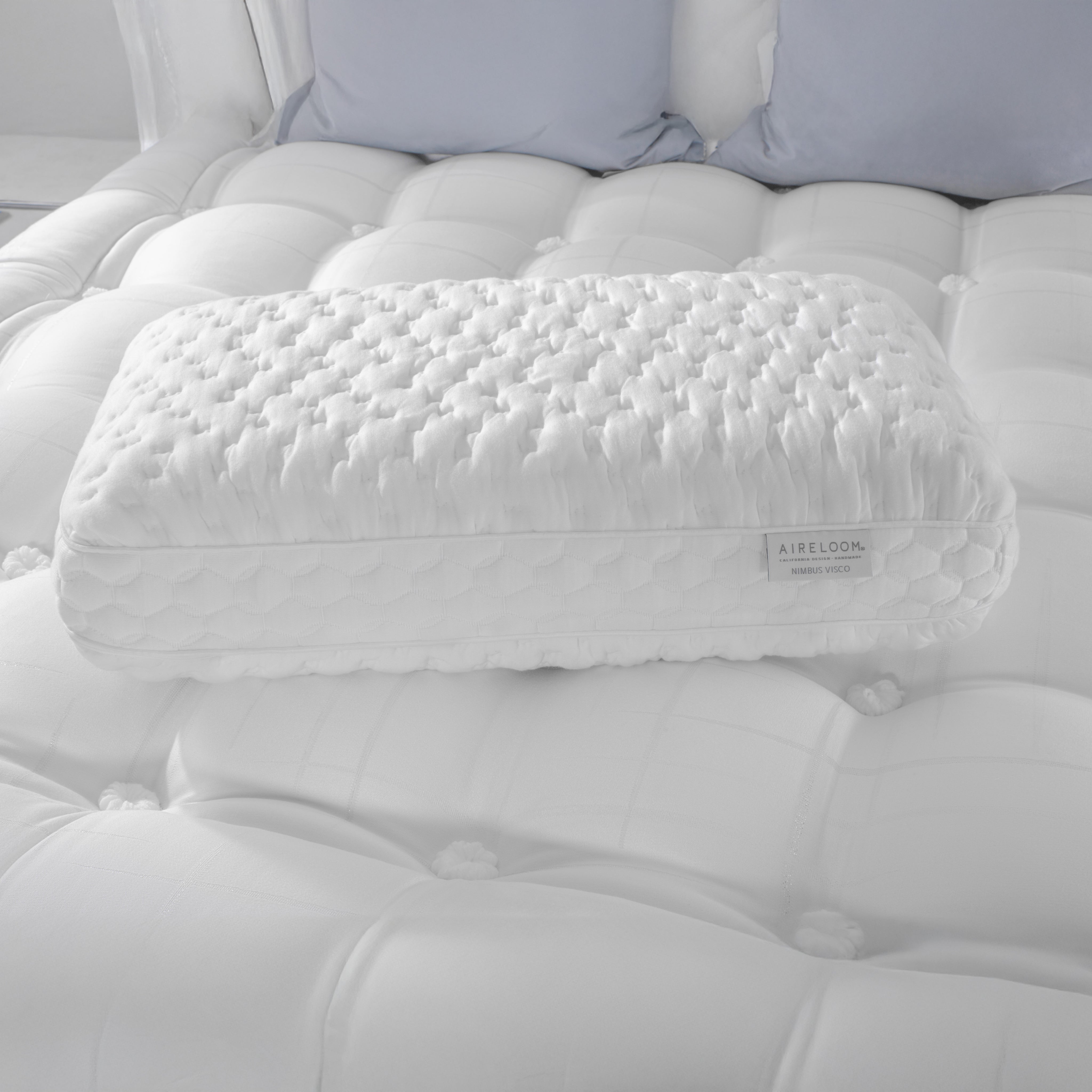 White quilted pillow on a tufted white mattress with 'Aireloom' branding.