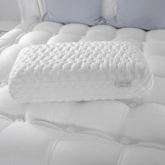 White quilted pillow on a tufted white mattress with 'Aireloom' branding.