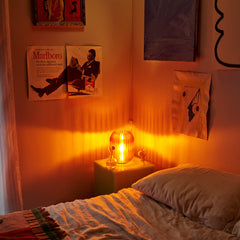 Bedroom with warm lighting, Marlboro advertisement on wall, and lit lamp.