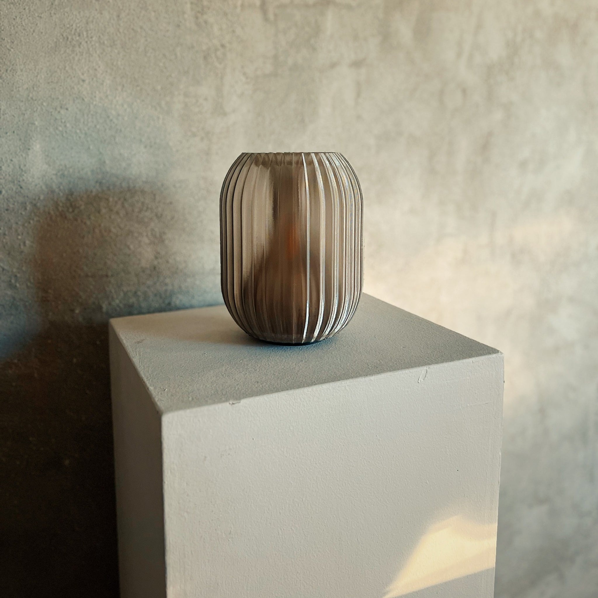 Glass vase on a white pedestal against a textured wall