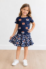 Young girl wearing a navy blue outfit with a checkered skirt on a white background