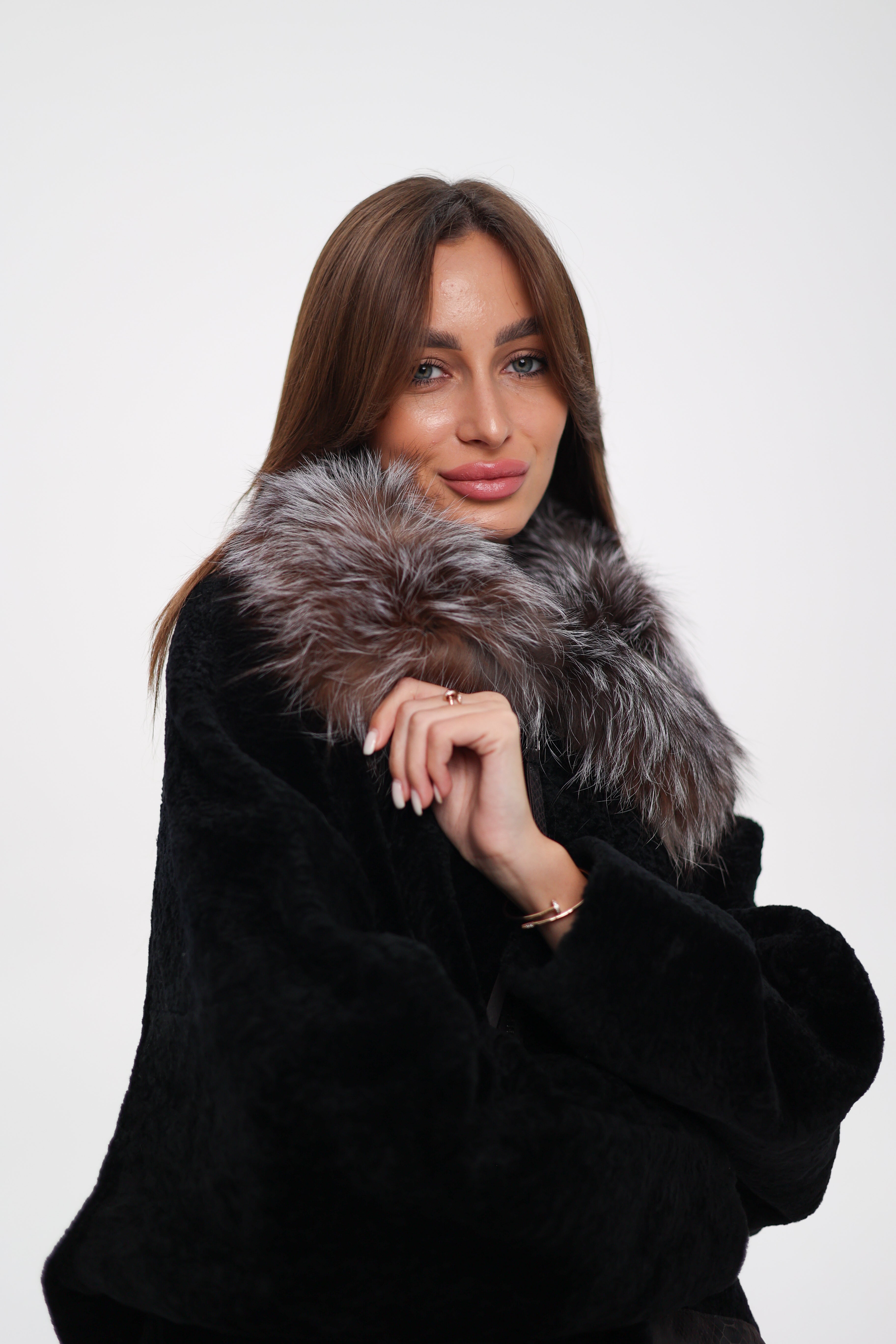 Woman wearing a black coat with a fur collar on a white background