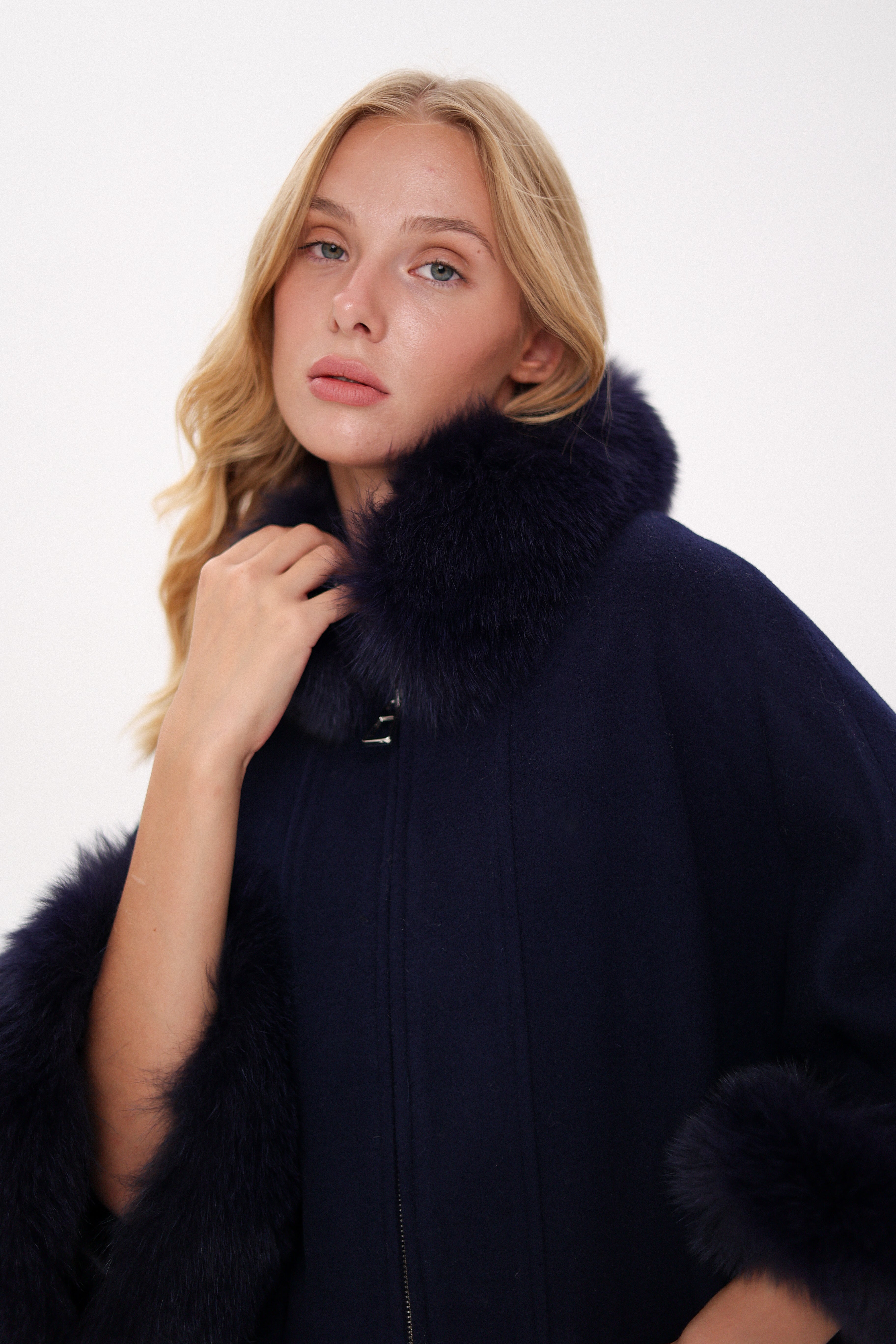 Woman wearing a dark blue coat with fur collar on a white background