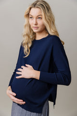 Pregnant woman wearing a navy blue top against a beige background