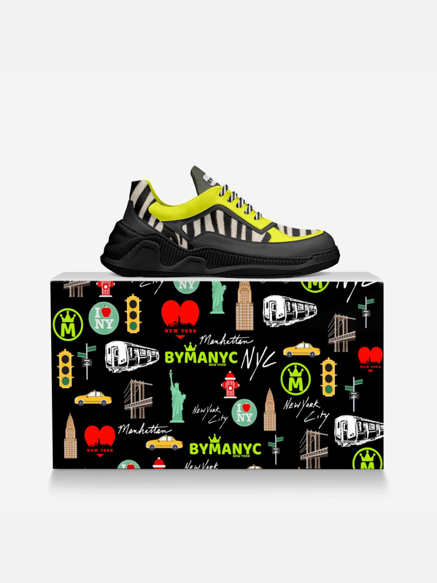 Black sneaker with yellow accents on a decorative box featuring New York City icons.