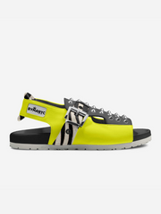 Neon yellow sandal with black straps and spikes on a white background