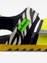 Sandal with zebra pattern strap and green 'BY MANYC' label on a white background