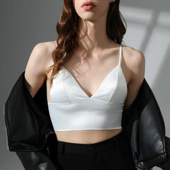 Person wearing a white sports bra and black jacket against a neutral background