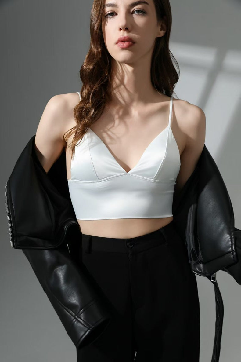 Woman wearing a white crop top and black jacket against a gray background