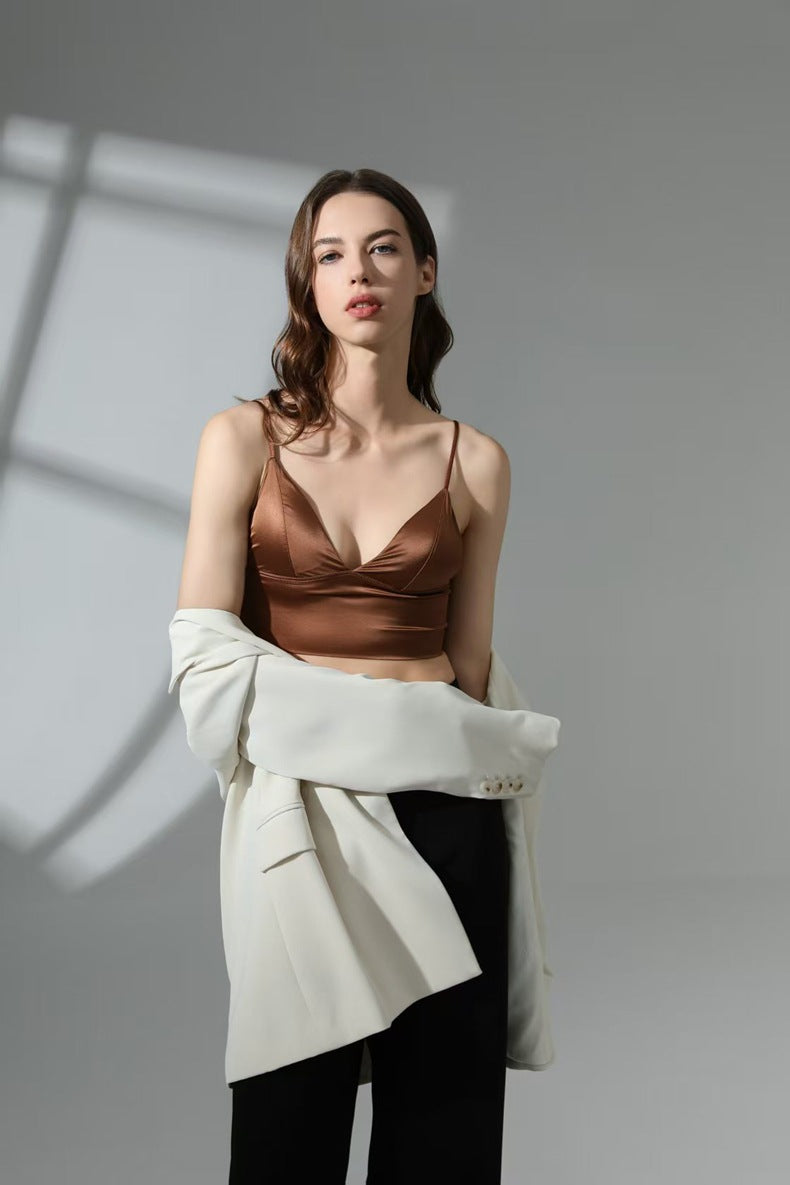 Woman wearing a brown top and white jacket against a gray background