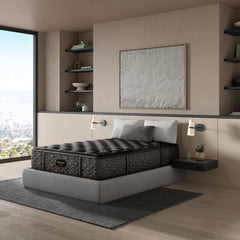Mattress on a bed in a modern bedroom with large windows and shelves.
