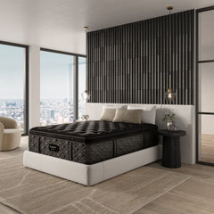 Black mattress on a white bed frame in a modern bedroom with large windows and decorative elements.