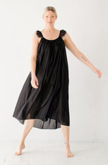 Woman wearing a black dress with sheer sleeves on a white background