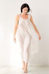 Woman wearing a white sleeveless dress against a plain background