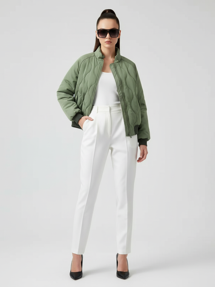 Woman wearing a green jacket, white top, and white pants on a white background