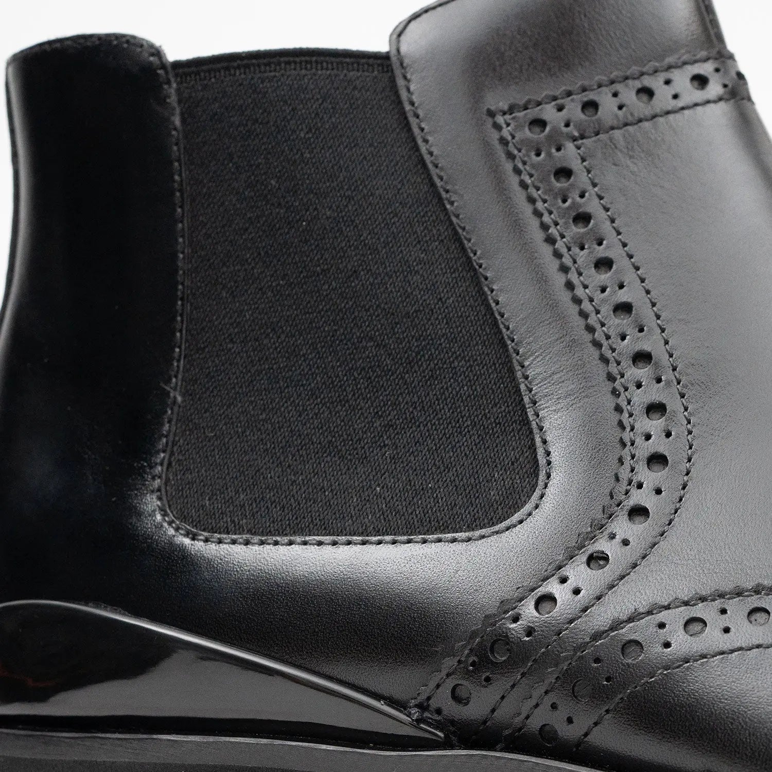 Close-up of a black leather shoe with detailed stitching on a white background