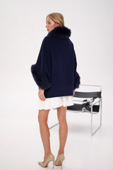 Woman wearing a navy blue sweater with fur trim on a white background