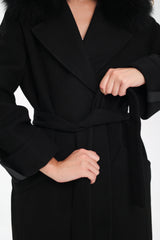 Black coat with a belt being adjusted on a white background