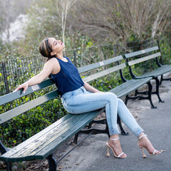 Woman sitting on a bench in a park with trees and a fence in the background