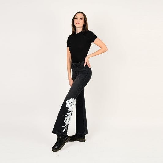 Woman wearing black t-shirt and black jeans with white floral design on a white background