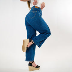 Person wearing blue jeans and platform shoes on a white background