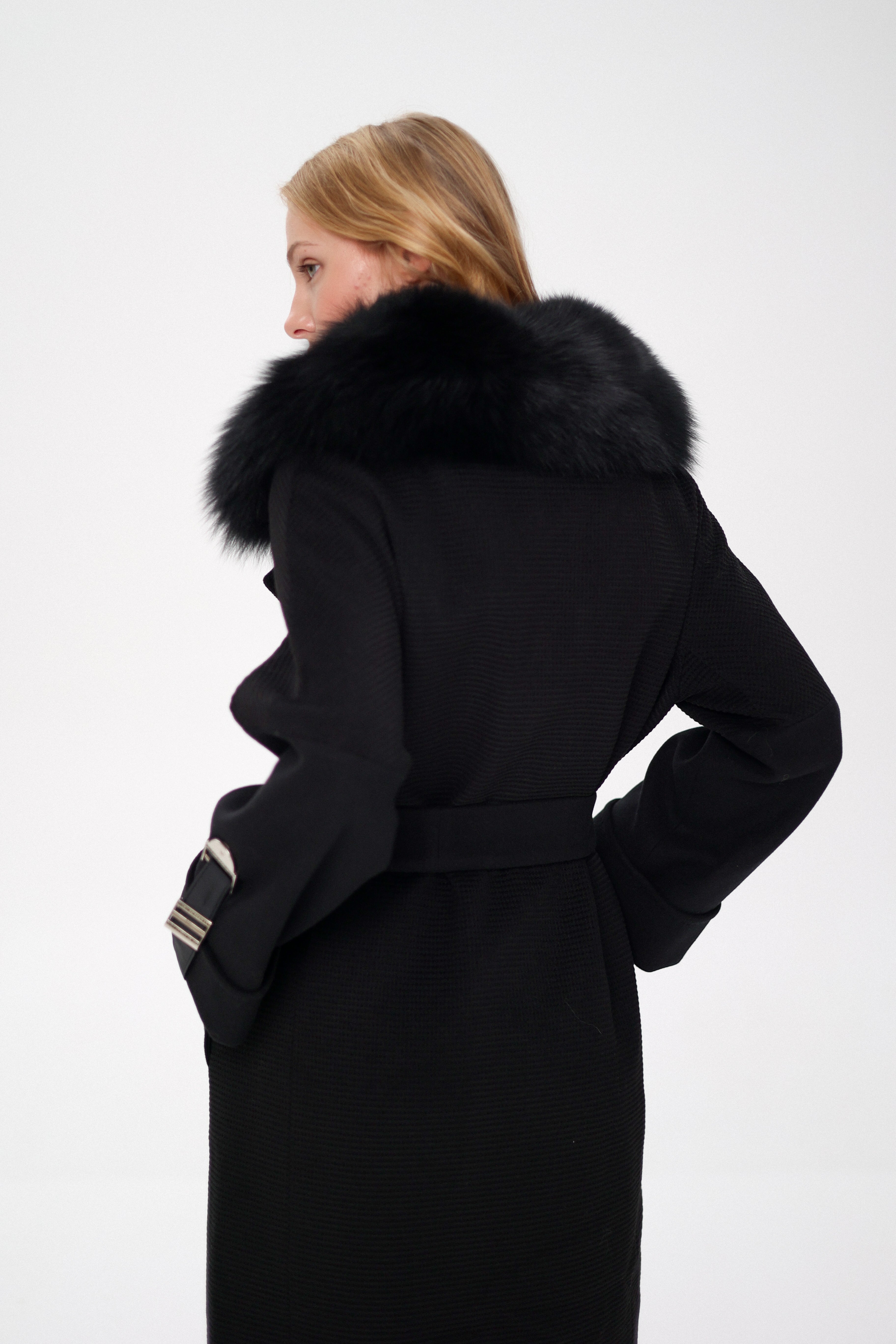 Woman wearing a black coat with a fur-lined hood on a white background