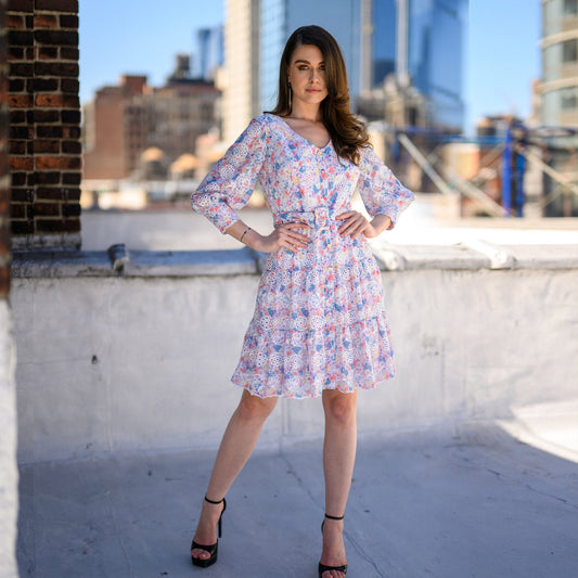 Woman in a floral dress standing on a rooftop with cityscape in the background