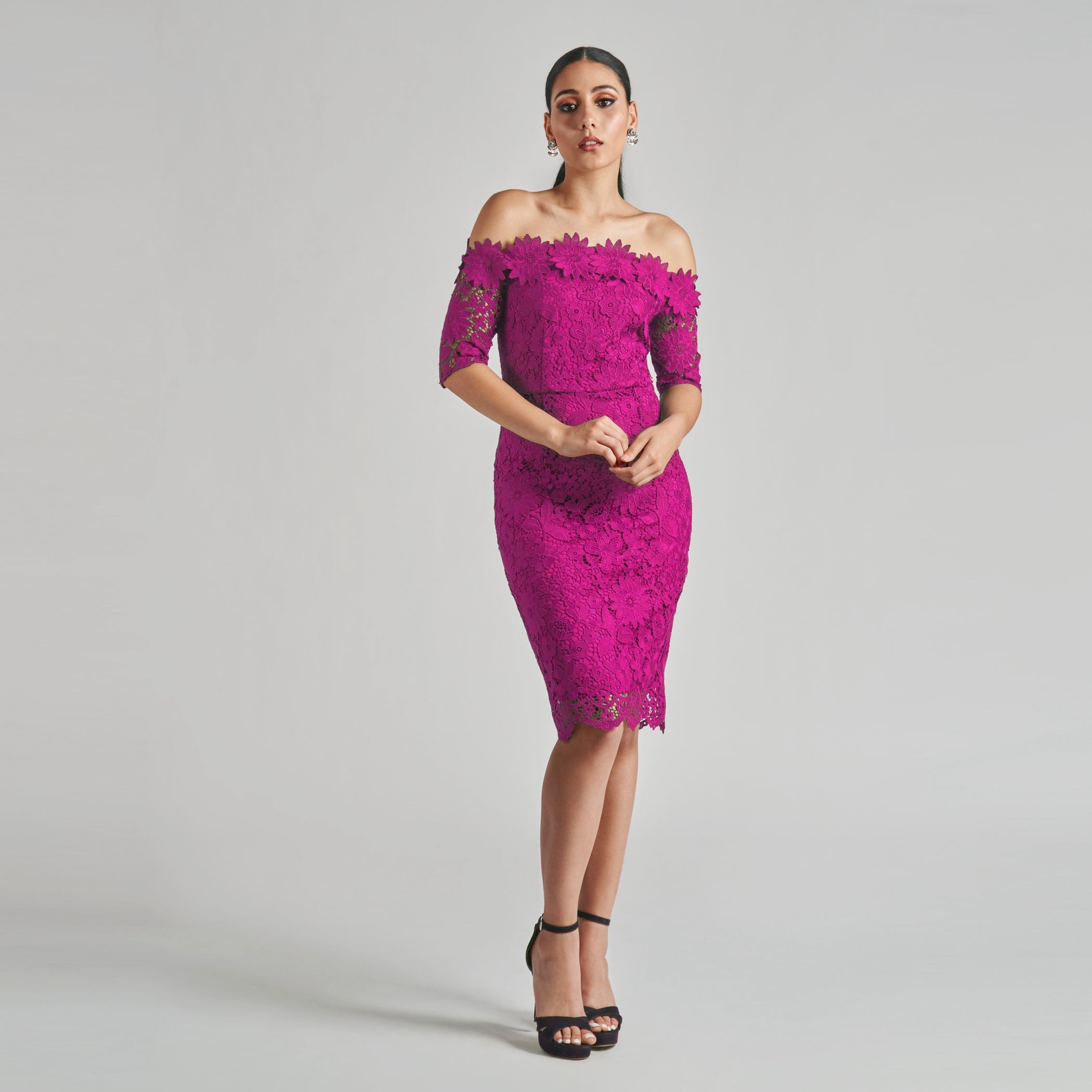 Woman wearing a pink lace dress against a gray background