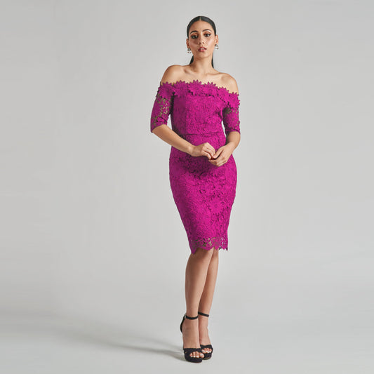 Woman wearing a pink lace dress against a gray background