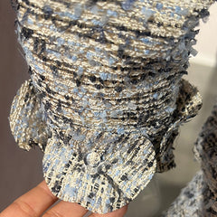 Close-up of a textured, silver and black decorative item held by a hand.