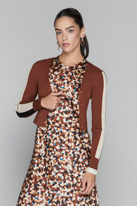 Woman wearing a brown blazer over a patterned dress on a gray background