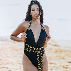 Woman wearing a black swimsuit with yellow accents on a beach