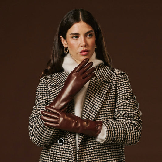 Woman wearing a checkered coat and brown leather gloves against a dark background