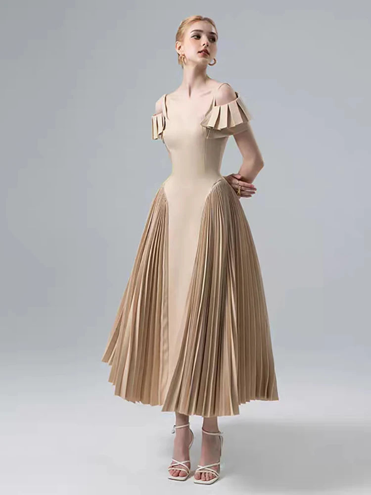 Woman wearing a beige dress with pleated skirt on a light gray background