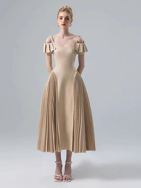 Woman wearing a beige dress with ruffled sleeves on a gray background