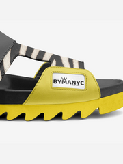 Yellow and black slide sandal with zebra pattern strap and ByManyc logo on a white background