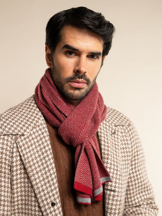 Man wearing a red scarf and patterned coat against a beige background