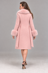 A woman shown from the back wearing a light pink mid-length coat with fluffy faux-fur trim around the collar and cuffs, paired with black high-heeled sandals, against a neutral gray studio background.