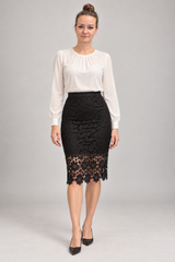 A woman modeling a white long-sleeve blouse and a black lace knee-length skirt against a light gray studio background.