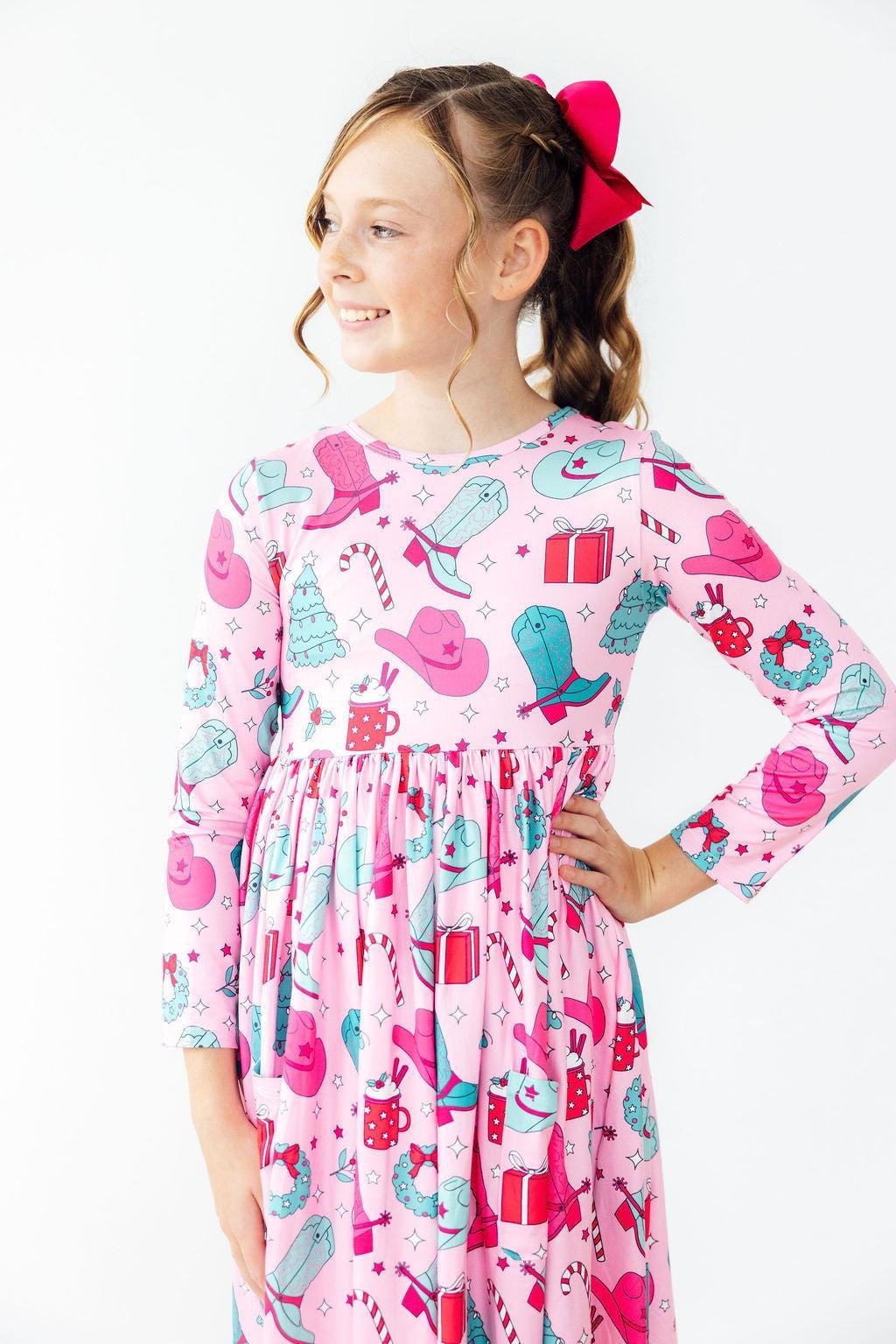 Young girl wearing a pink dress with cowboy print on a white background