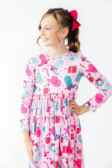 Young girl wearing a pink dress with cowboy print on a white background