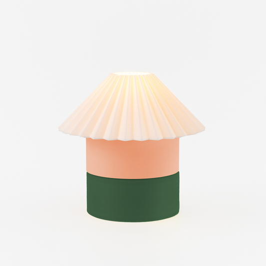 Decorative lamp with a white shade, peach body, and green base on a light beige background