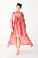 Woman wearing a pink nightgown and robe on a white background