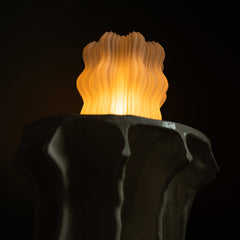Decorative lamp with wavy design and warm glow on a dark background