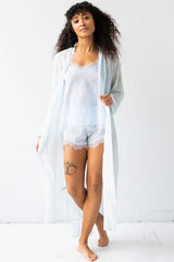 Woman wearing a light blue lace nightgown with a matching robe on a white background