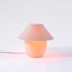 Table lamp with a pink shade and base on a light gray background